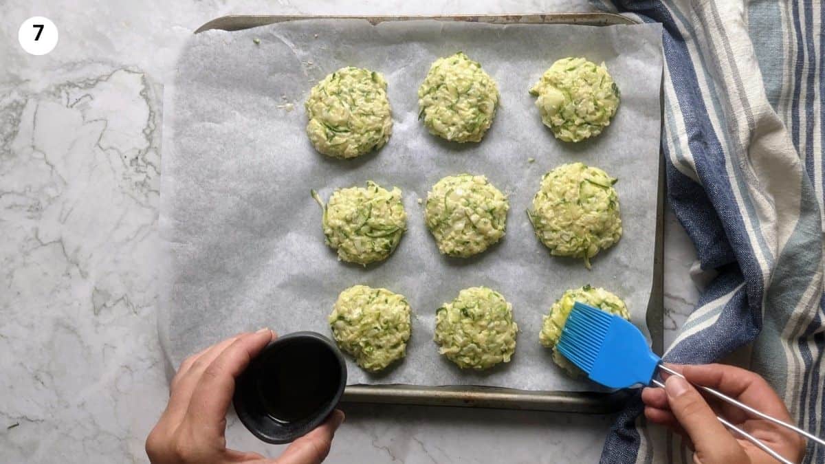 Brushing the zucchini fritters with oil before placing into the oven.