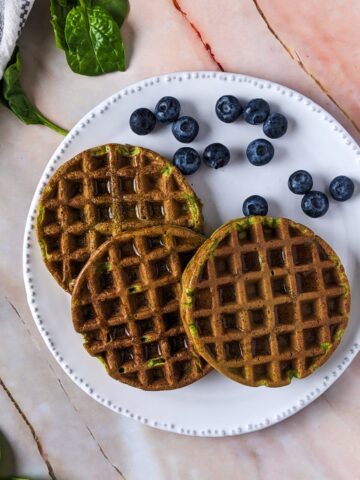Spinach waffles served on white plate with blueberries.