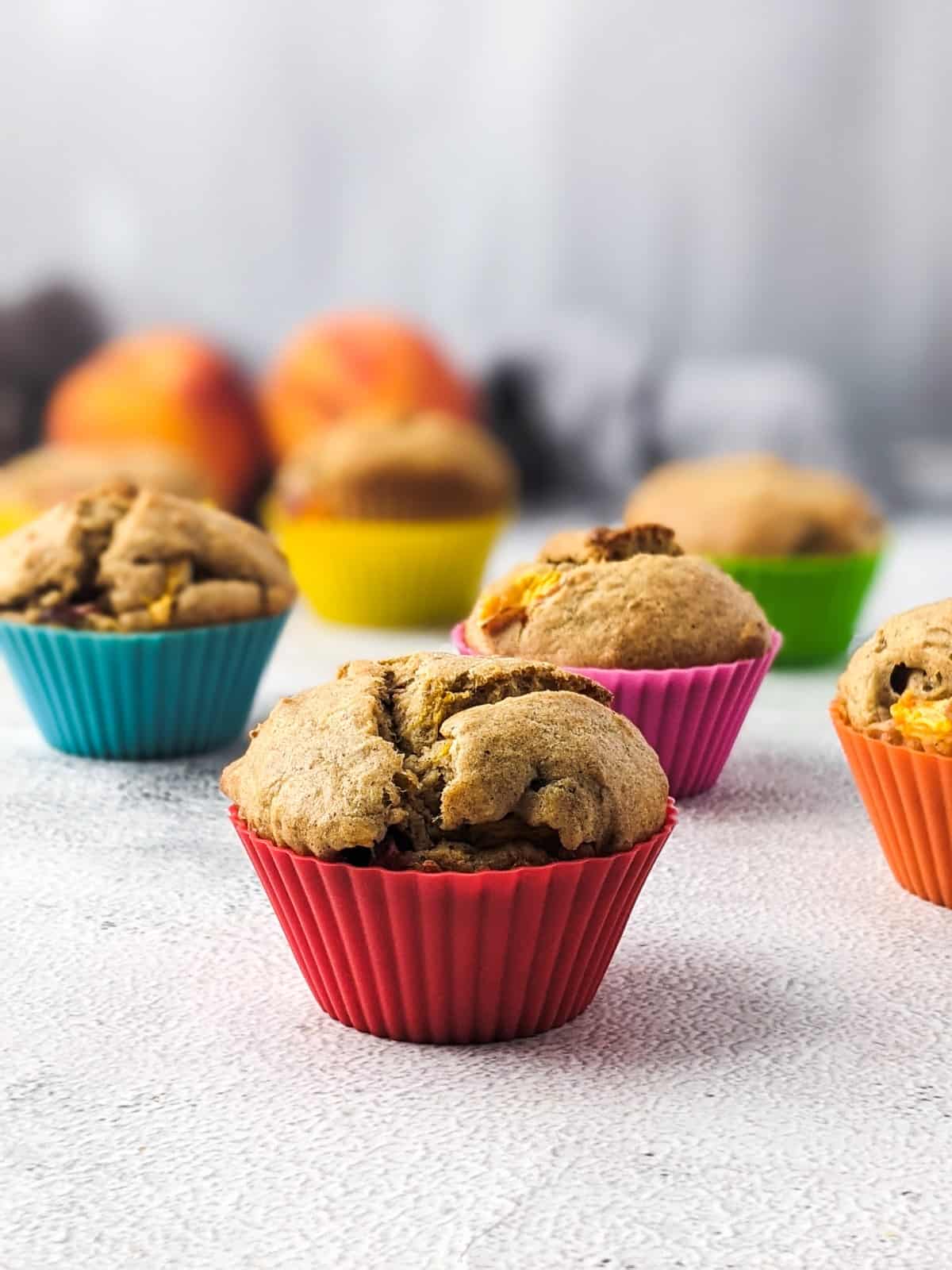 Sugar-free peach muffins on the table in colorful muffin cases one next to the other.