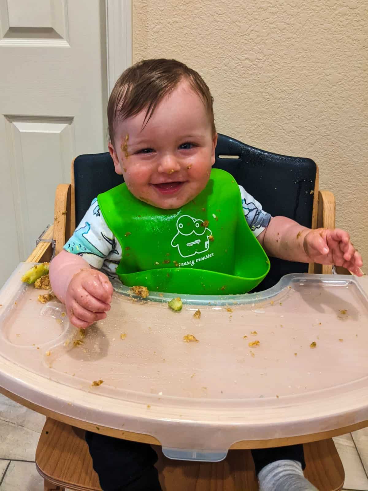 Baby after finishing his food with a dirty face and hands.