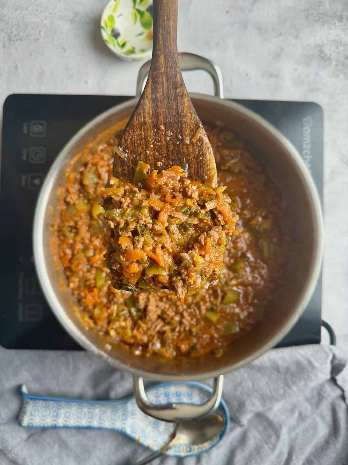 Veggie loaded bolognese ready with wooden spatula showing the sauce.