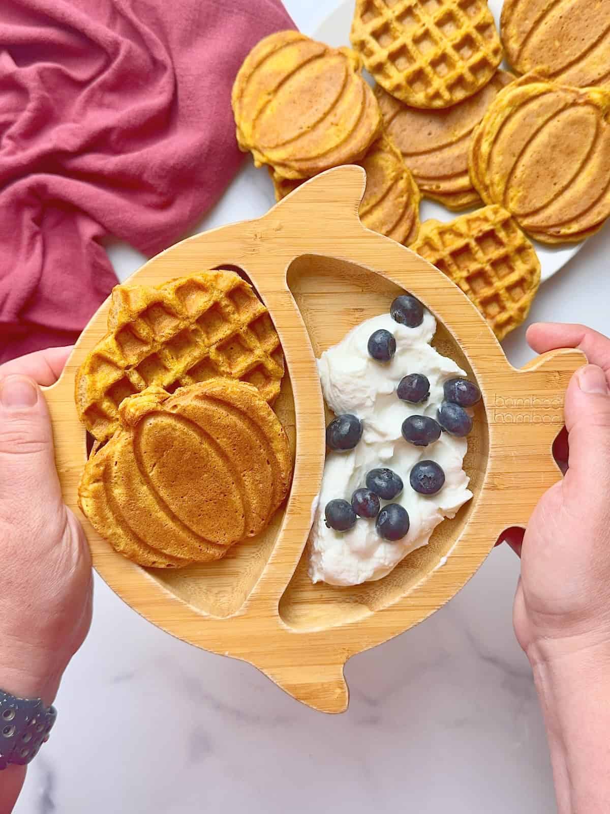 Pumpkin spice waffles served in bamboo plate with yogurt and blueberries.