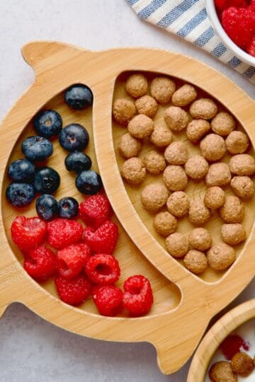 Strawberry puffs served on bamboo plate with raspberries and blueberries.