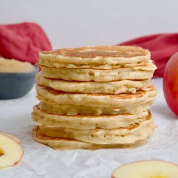Stack of apple pancakes next to apple slices.