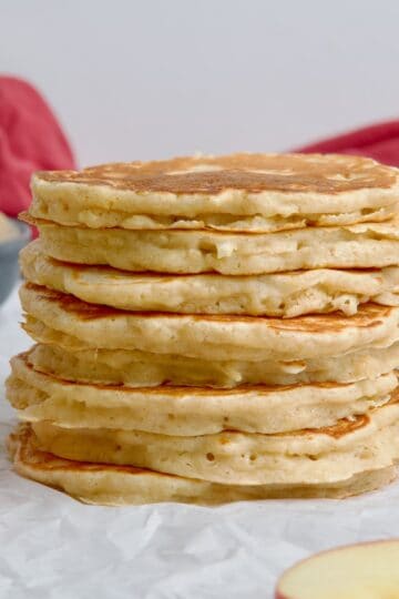 Stack of apple pancakes next to apple slices.