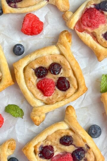 Berry cream cheese pastries with berries and mint leaves between them.