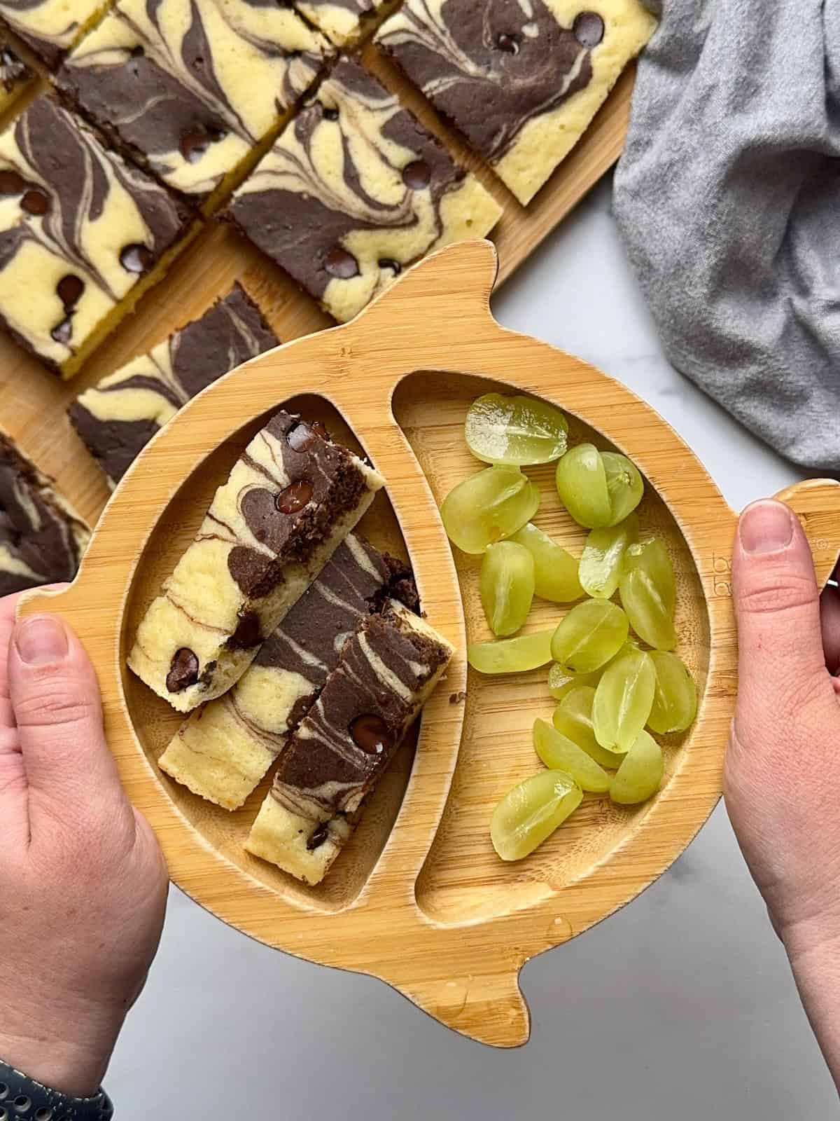 Chocolate sheetpan pancake served on bamboo plate with grapes.