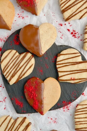 Heart-shaped butter cookies with chocolate decoration and dried raspberries sprinkled on top.