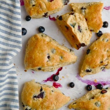 Blueberry scones on parchment paper with blueberries between them.