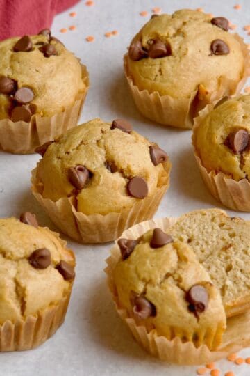 Lentil muffins in brown muffin cases next to orange lentils.