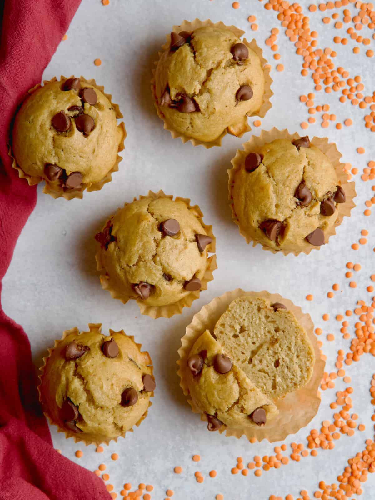 Lentil muffins in brown muffin cases next to orange lentils.