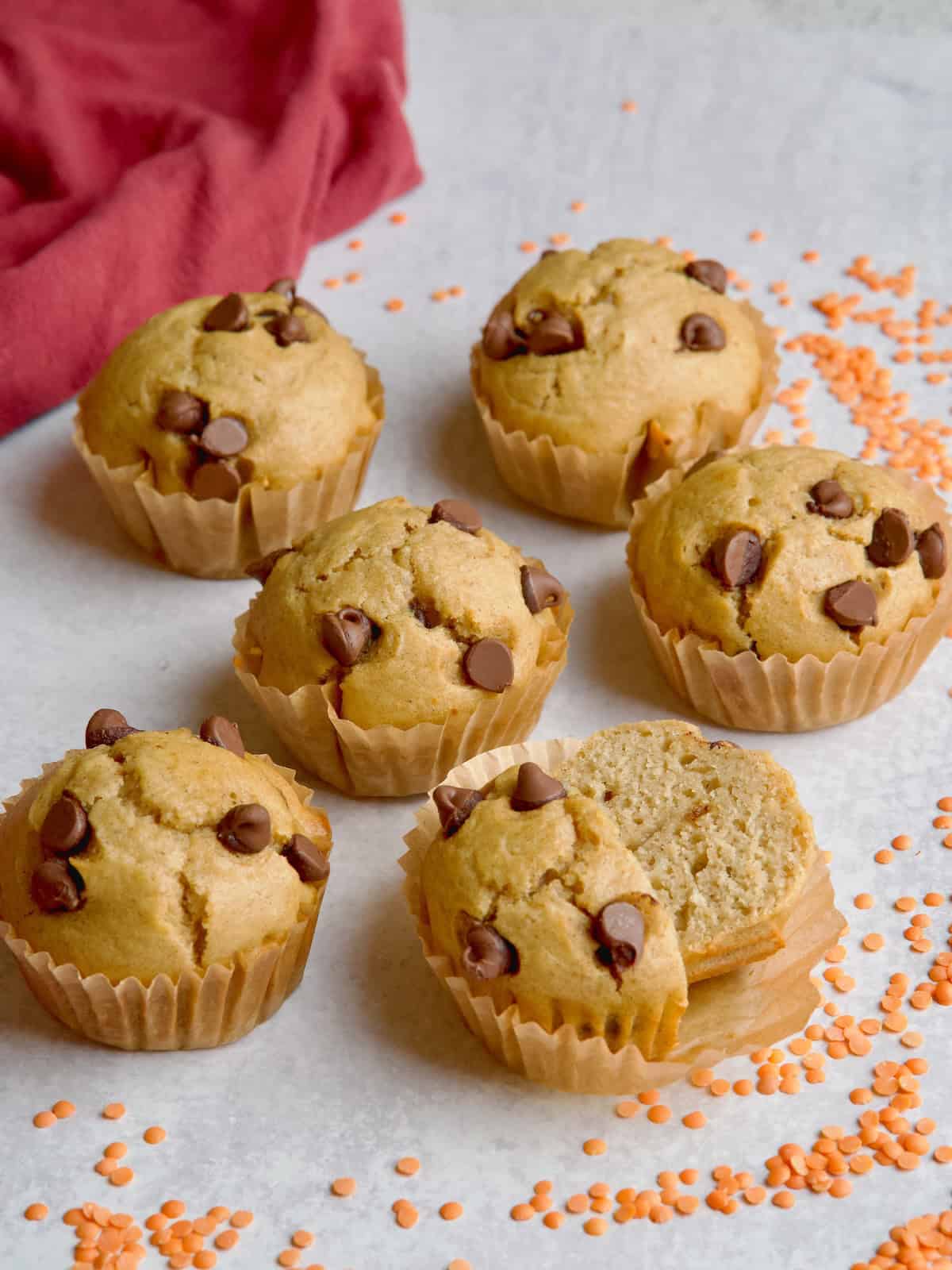 Lentil muffins in brown muffin cases next to orange lentils.