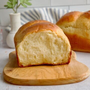 Milk bread with a slice cut on a wooden board.