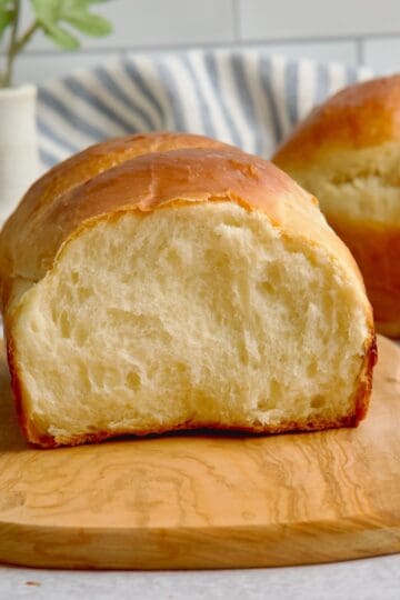 Milk bread with a slice cut on a wooden board.