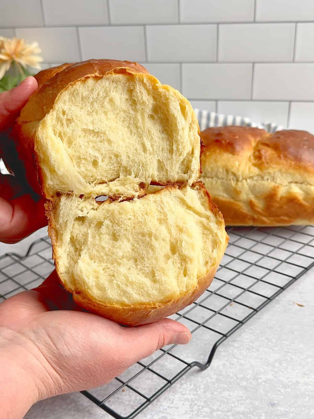 Hands holding milk bread cut in half.