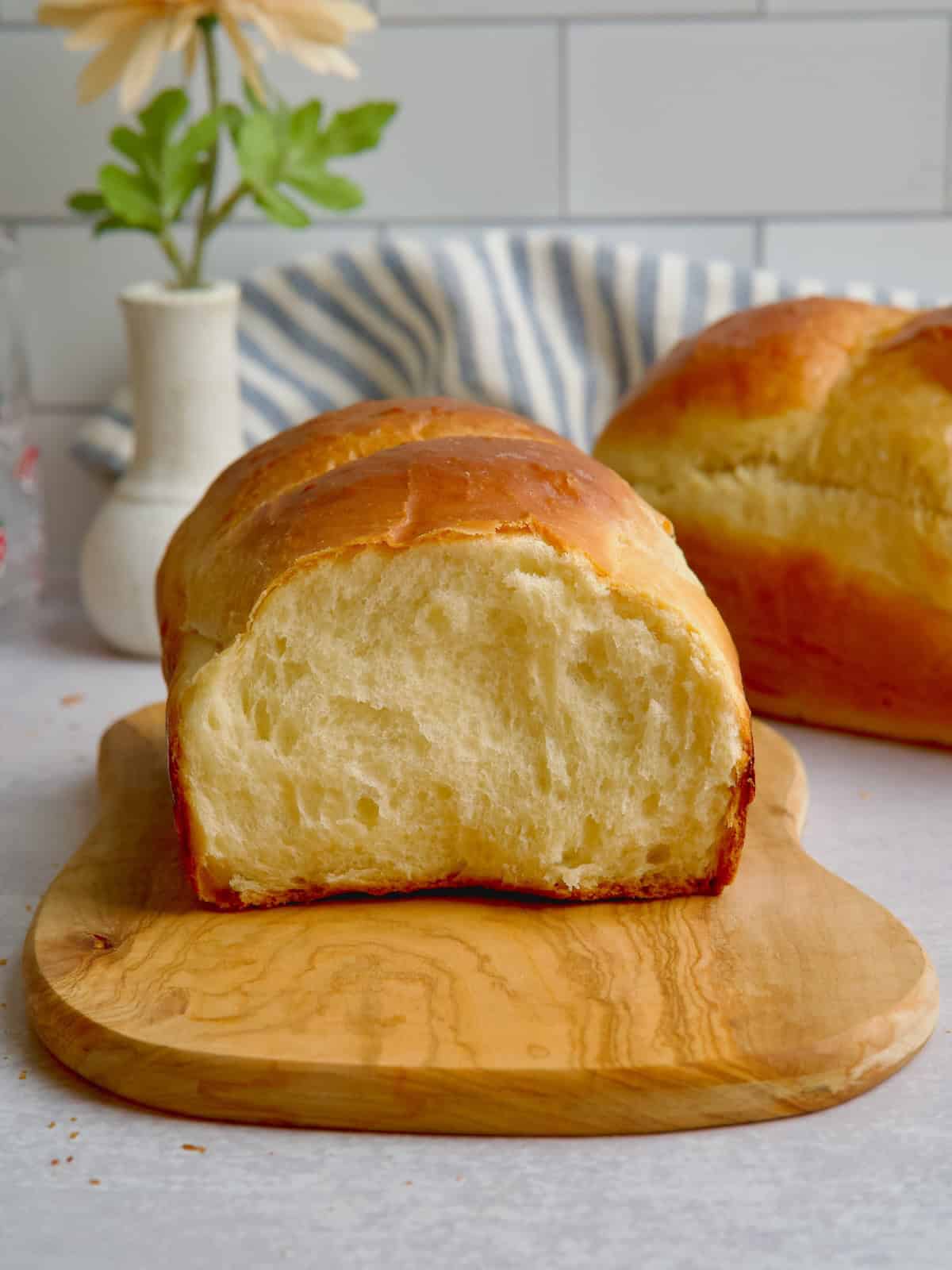 Milk bread with a slice cut on a wooden board.