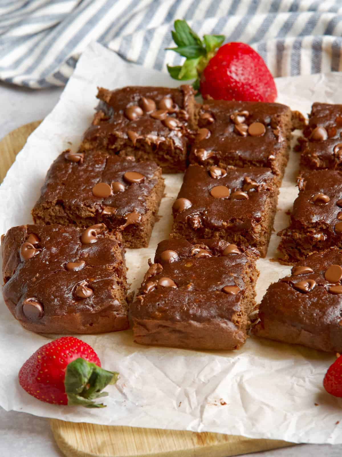 Chocolate square cake slices with strawberries between them.