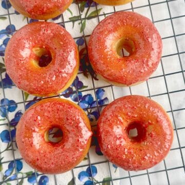 Baked donuts with strawberry glaze on a wire rack.