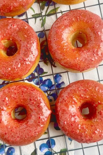 Baked donuts with strawberry glaze on a wire rack.