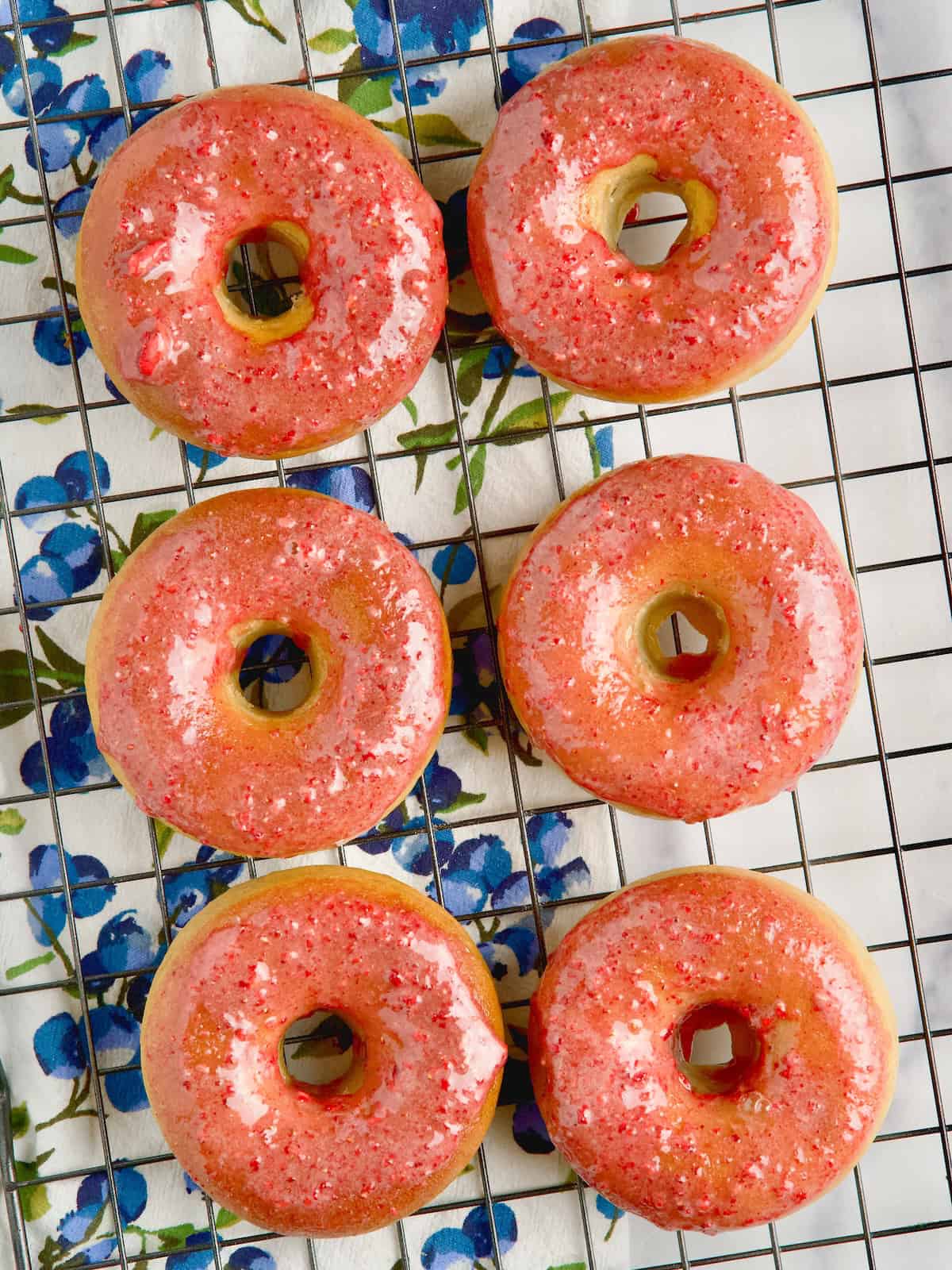 Baked donuts with strawberry glaze on a wire rack.
