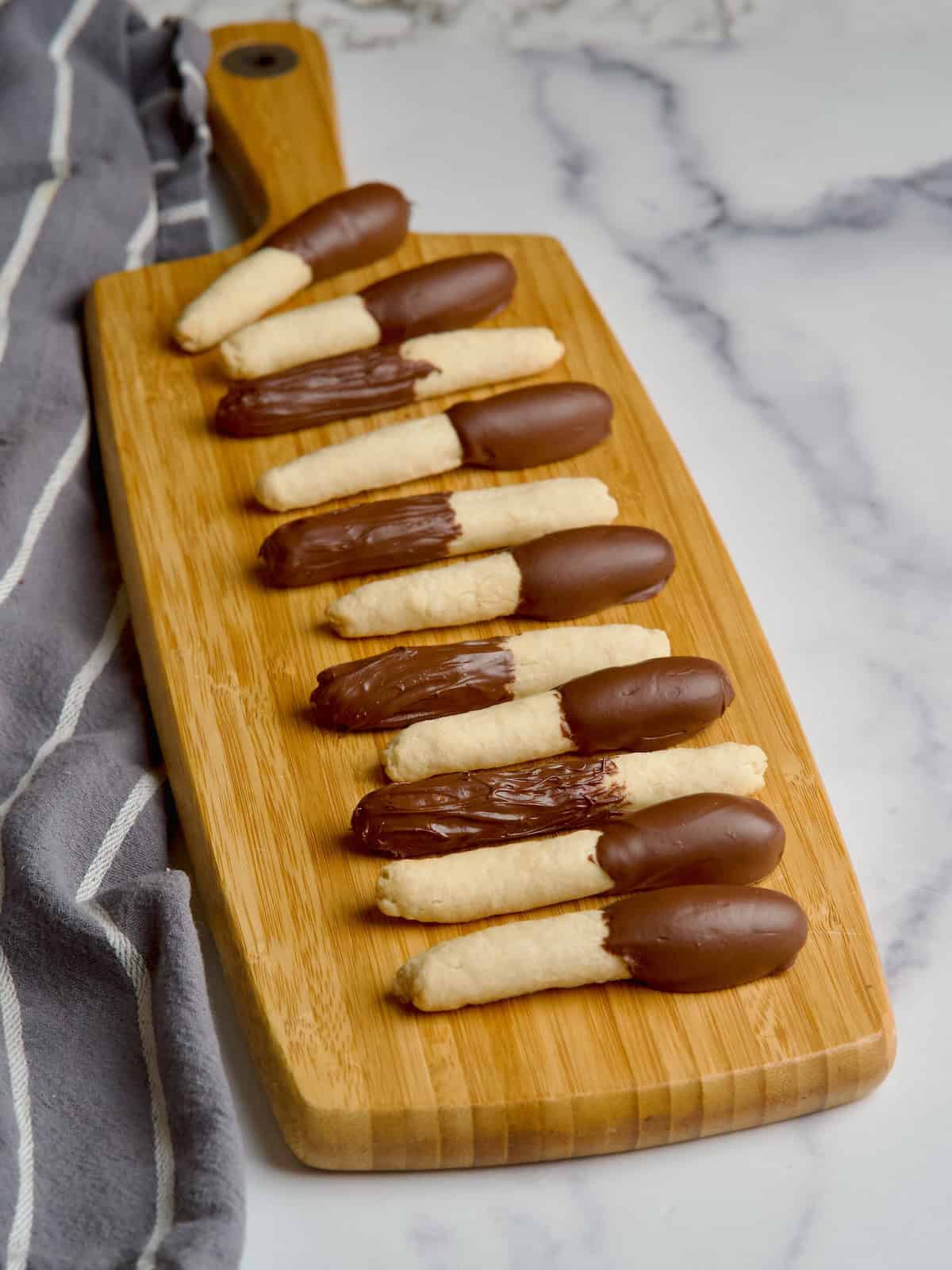 Half covered chocolate cookie sticks on a board next to each other.