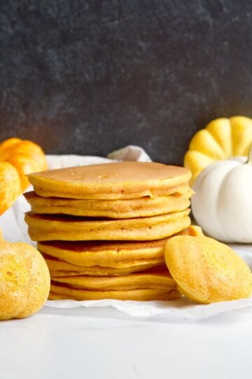 Pumpkin pancakes stack next to pumpkin shaped pancakes.