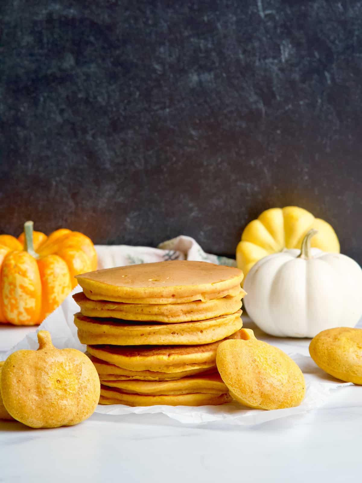 Pumpkin pancakes stack next to pumpkin shaped pancakes.